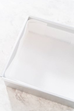 Yumurta likörü hazırlamak için kare cheesecake tavasını parşömen kağıdıyla kaplamak.
