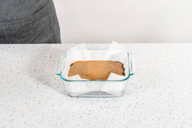 Çikolatalı fıstık ezmeli şekerleme hazırlamak için parşömen kağıdıyla kaplı fırın tavasına şekerleme döküyorum..