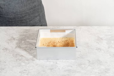 Parşömenle kaplanmış kare bir cheesecake tavasından eggnog şekerlemesi kaldırılıyor.