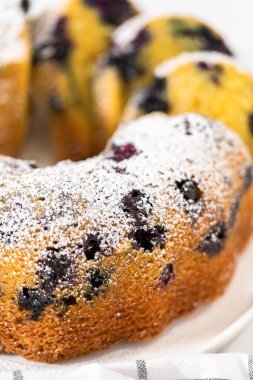 Taze pişmiş limonlu yaban mersinli kek dilimliyorum. Pudra şekerli..