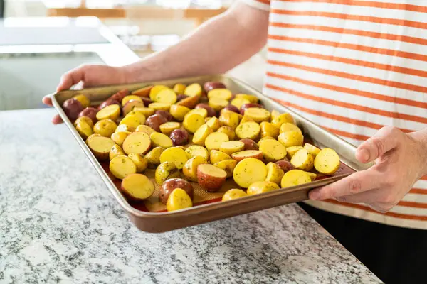 モダンなキッチンでは 半分にされた多色の大理石のジャガイモが シリコーンライナーを並べたベーキングパンに配置されています ローストプロセスは キッチンに口の香りを注入します — ストック写真