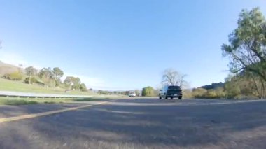 Santa Maria, California, ABD-6 Aralık 2022-Kış gününde San Luis Obispo, Kaliforniya yakınlarındaki ikonik 1. Otoyol boyunca bir araba ilerliyor. Çevresindeki manzara kahverengimsi ve bastırılmış.