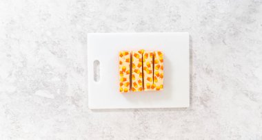 Düz yatıyordu. Beyaz bir kesme tahtasının üzerinde şekerli mısır şekerini kare parçalara ayırmak..