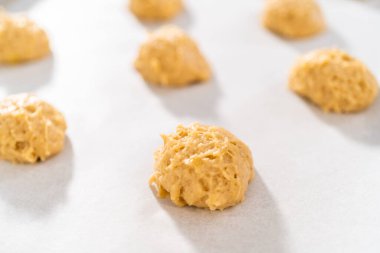 Kurabiye hamuru kepçesiyle kurabiye hamuru pişirip parşömen kağıdıyla kaplanmış bir tepsiye koyup muzlu kurabiyeleri çikolatalı çiselemek..