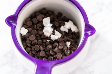 Çikolata parçalarını eritip, eritip, pandaya benzeyen kurabiyeler yapmak için çikolata kreması yapmak..