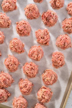 Fırında pişmiş köfte hazırlamak için parşömen kağıdıyla kaplı hamur kepçesiyle kıyma kepçesi yapmak..
