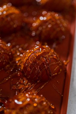 Drizzling caramelized sugar on top of silicone molds to make caramel cupcake toppers.