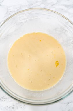 Amerikan bayrağı mini kekleri yapmak için ıslak malzemeleri büyük bir bardakta karıştırıyorum..