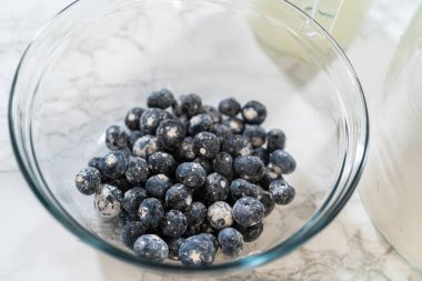 Cam bir kasenin içindeki bileşenleri birleştirmek, bir çırpıcıyla karıştırmak, limonlu-yabanmersinli kek hazırlamak..