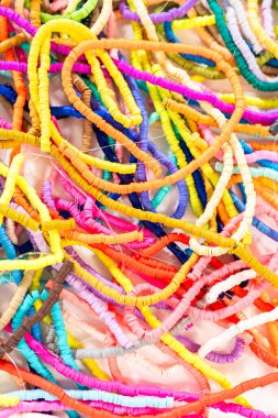 Beyaz bir masadaki renklere göre düzenlenmiş canlı bir kil boncuk koleksiyonu genç zanaatkarlara kendi eşsiz bileziklerini yapmaları için ilham vermeye hazır..