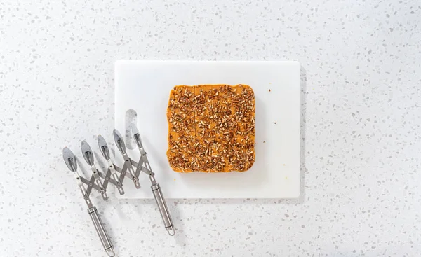 Flat lay. Scoring pumpkin spice fudge using a wheel dough cutter for cutting into small pieces.