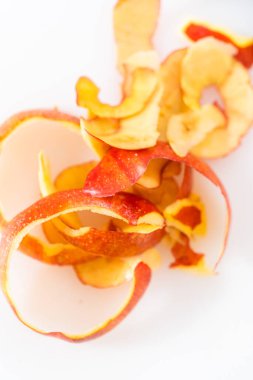 Beyaz bir kesim tahtasının üzerinde patates soyacağı ile kırmızı elmalardan deri soyuyorlar..