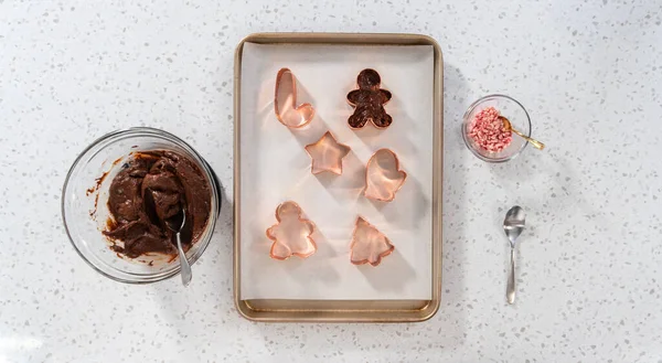 Flat lay. Filling cookie cutter with fudge mixture to prepare Christmas cookie-cutter peppermint fudge.