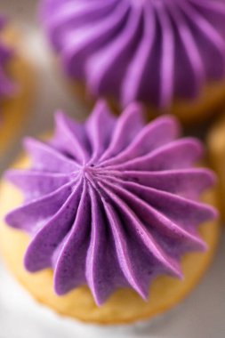 Beyaz pasta standında pembe tereyağlı taze pişmiş mini vanilyalı kekler..