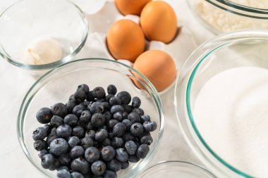 Limonlu yaban mersinli kek pişirmek için bardakların içindeki ölçülü malzemeler..