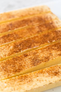 Beyaz bir kesme tahtasıyla eggnog şekerlerini küçük parçalara ayırmak.