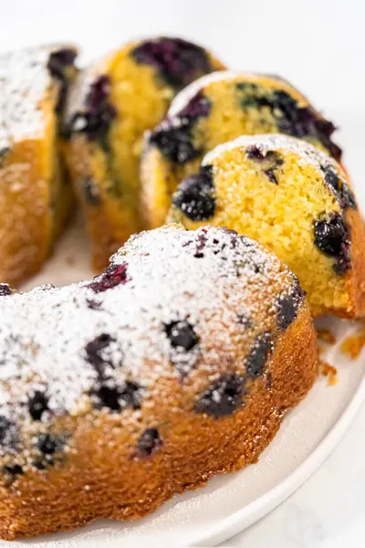 Taze pişmiş limonlu yaban mersinli kek dilimliyorum. Pudra şekerli..