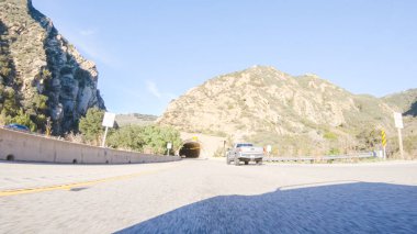 Los Angeles, California, ABD-4 Aralık 2022-POV açık mavi gökyüzünün altında Kaliforniya El Capitan State Beach yakınlarında HWY 101 'de sürüş yapmak manzaranın büyüleyici manzarasını sunuyor.