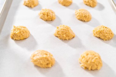 Kurabiye hamuru kepçesiyle kurabiye hamuru pişirip parşömen kağıdıyla kaplanmış bir tepsiye koyup muzlu kurabiyeleri çikolatalı çiselemek..