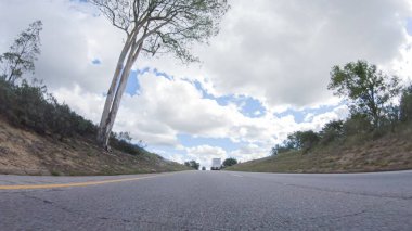 Açık bir kış gününde, bir araba, Santa Maria, California yakınlarındaki 101. Otoyol boyunca yeşil ve altın renkli bir karışımla çevrili, parlak mavi bir gökyüzünün altında sorunsuzca seyahat eder..