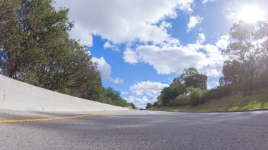 Açık bir kış gününde, bir araba, Santa Maria, California yakınlarındaki 101. Otoyol boyunca yeşil ve altın renkli bir karışımla çevrili, parlak mavi bir gökyüzünün altında sorunsuzca seyahat eder..