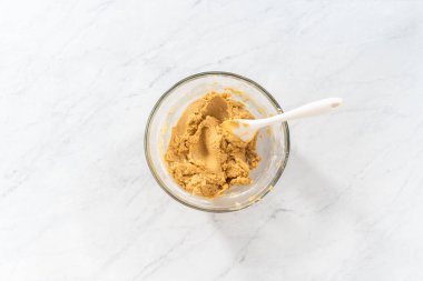 Düz yatıyordu. Islak ve kuru malzemelerle karıştırılmış cam bir kabın içinde çırpılmış beyaz çikolatalı makadamia fındığı..