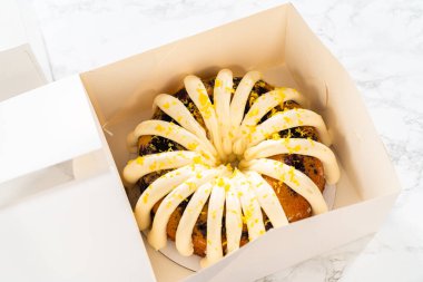 Taze pişmiş kekler beyaz kağıt kutulara dikkatlice yerleştirilir ve lezzetli görünümlerini korurken onları güvenli bir şekilde ulaşıma hazırlarlar..