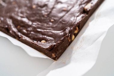 Parşömenle kaplı kare bir peynirli kek tavasından çikolatalı macadamia şekerlemesi çıkarıyorum..