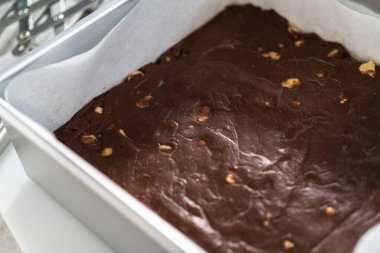 Parşömen kağıdıyla kaplanmış kare bir tavada taze ev yapımı çikolatalı macadamia şekerlemesi..