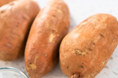 Fırında kızartılmış tatlı patates yapmak için cam karıştırma kabında ölçülmüş malzemeler.