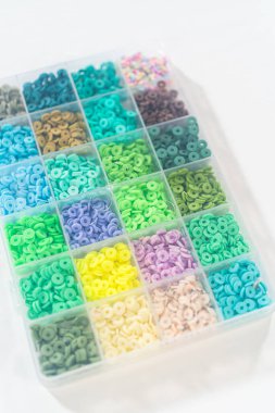 Beyaz bir masaya yerleştirilmiş çeşitli kil boncuk kutuları yaratıcı çocukların el sanatları projesini bekliyor..