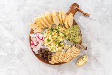 Düz yatıyordu. Sebzeli tereyağı tahtası ve tahta kesme tahtasında ekmek..