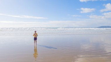 Küçük kız, soğuğa göğüs geriyor, kışın sahilde mayosuyla koşuyor..
