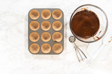 Düz yatıyordu. Lezzetli çikolatalı kekler yapmaya hazırlanırken, kek tepsisini kağıt kalemlerle dikkatlice diziyoruz, lezzetli bir ikram bizi bekliyor..