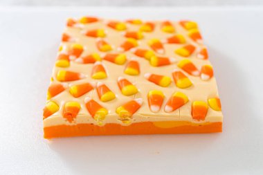 Beyaz bir kesme tahtasının üzerinde şekerli mısır şekerini kare parçalara ayırmak..