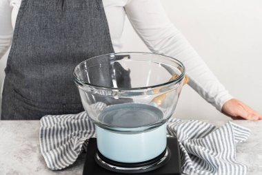 Eriyen beyaz çikolata parçacıkları ve diğer malzemeler kaynamış suyun üzerinde karışıp kızılcık fıstıklı şekerleme hazırlıyor..
