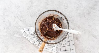 Düz yatıyordu. Beyaz çikolata parçacıkları ve diğer malzemeleri kaynayan suyun üzerine karıştırıp çikolatalı macadamia şekerlemesi hazırlıyorum..