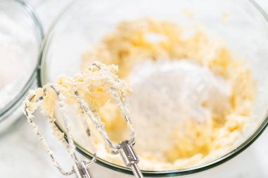 Zengin, pürüzsüz bir krem peynirli krema hazırlamak için el çırpma makinesi kullanarak malzemeleri ustalıkla birleştirirsin ki bu da kekin süslemesi için mükemmeldir..