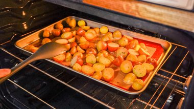 Modern bir mutfak ortamında, genç bir adam şu anda fırında baharatlı gökkuşağı patatesi kızartılarak lezzetli bir yemeğe doğru önemli bir adım atıyor..