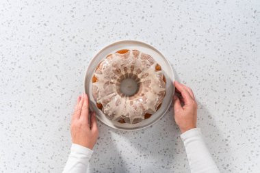 Flat lay. Freshly baked simple vanilla bundt cake with a white glaze on a serving plate.