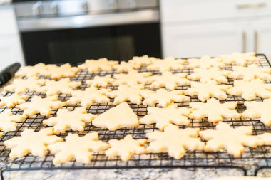 Lezzetli kar tanesi şekilli şekerli kurabiyeleri rafta soğutup onları Noel hediyelerine hazırlıyorum..