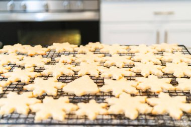 Lezzetli kar tanesi şekilli şekerli kurabiyeleri rafta soğutup onları Noel hediyelerine hazırlıyorum..