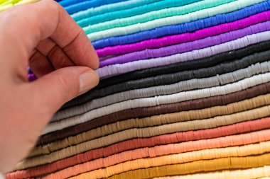 Beyaz bir masadaki renklere göre düzenlenmiş canlı bir kil boncuk koleksiyonu genç zanaatkarlara kendi eşsiz bileziklerini yapmaları için ilham vermeye hazır..