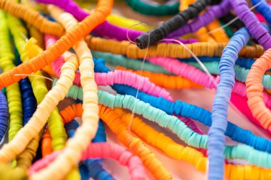 Beyaz bir masadaki renklere göre düzenlenmiş canlı bir kil boncuk koleksiyonu genç zanaatkarlara kendi eşsiz bileziklerini yapmaları için ilham vermeye hazır..