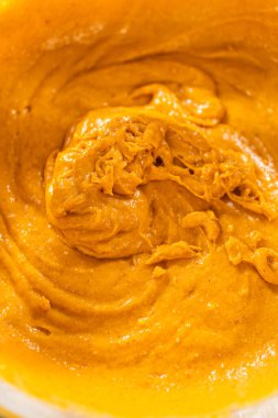 Ağız sulandırıcı ev yapımı balkabağı pastası için büyük bir karıştırma kabında ustalıkla harmanlanmış malzemelerin yakın çekimi..