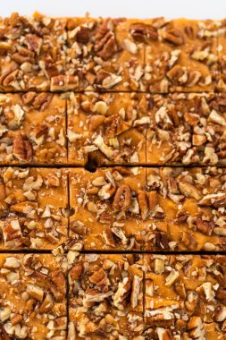 Beyaz bir kesme tahtasında balkabağı baharatlı şekerlemeyi kare parçalara ayırmak..