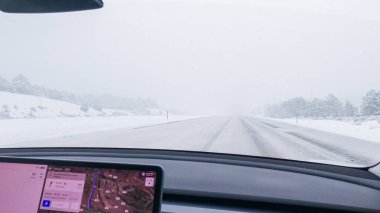 Denver, Colorado, ABD-7 Aralık 2022 bir Tesla elektrikli arabasıyla, bir sürücü kış fırtınası sırasında Batı Coloradoslar 'ın karlı arazilerinde doğru düzgün yol alır..