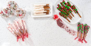 Denver, Colorado, USA-December 18, 2022-Flat lay. Packaging homemade chocolate-covered pretzels into clear plastic bags for Christmas gifts.