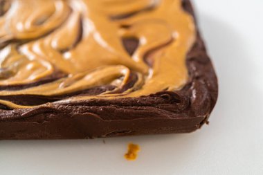 Removing chocolate fudge with peanut butter swirl from the baking pan lined with parchment