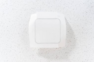 Düz yatıyordu. Sade şekerleme hazırlamak için cam fırın tavasını kağıt kağıtla kaplıyor..